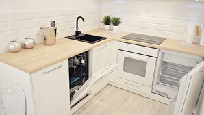 A modern kitchen with white cabinetry, a black sink, and a built-in oven. - Warsaw Concierge Opera Apartment (Warsaw)