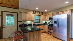 Una cocina moderna con armarios de madera, un refrigerador de acero inoxidable y una encimera de granito.