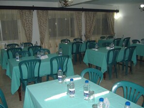 A conference room with rows of tables and chairs, each table set with water bottles and name tags. - Al Djadid (Domoni)
