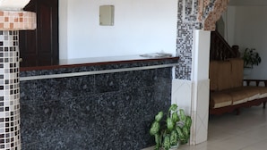A reception area with a tiled floor, a reception desk, a decorative ceiling, and a staircase. - Al Djadid (Domoni)