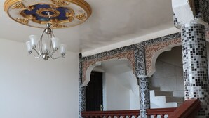 A staircase with a wooden handrail and a tiled wall with a mosaic pattern. - Al Djadid (Domoni)
