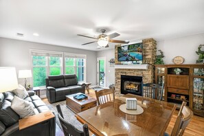 A living room with a fireplace, a television, and a dining area.