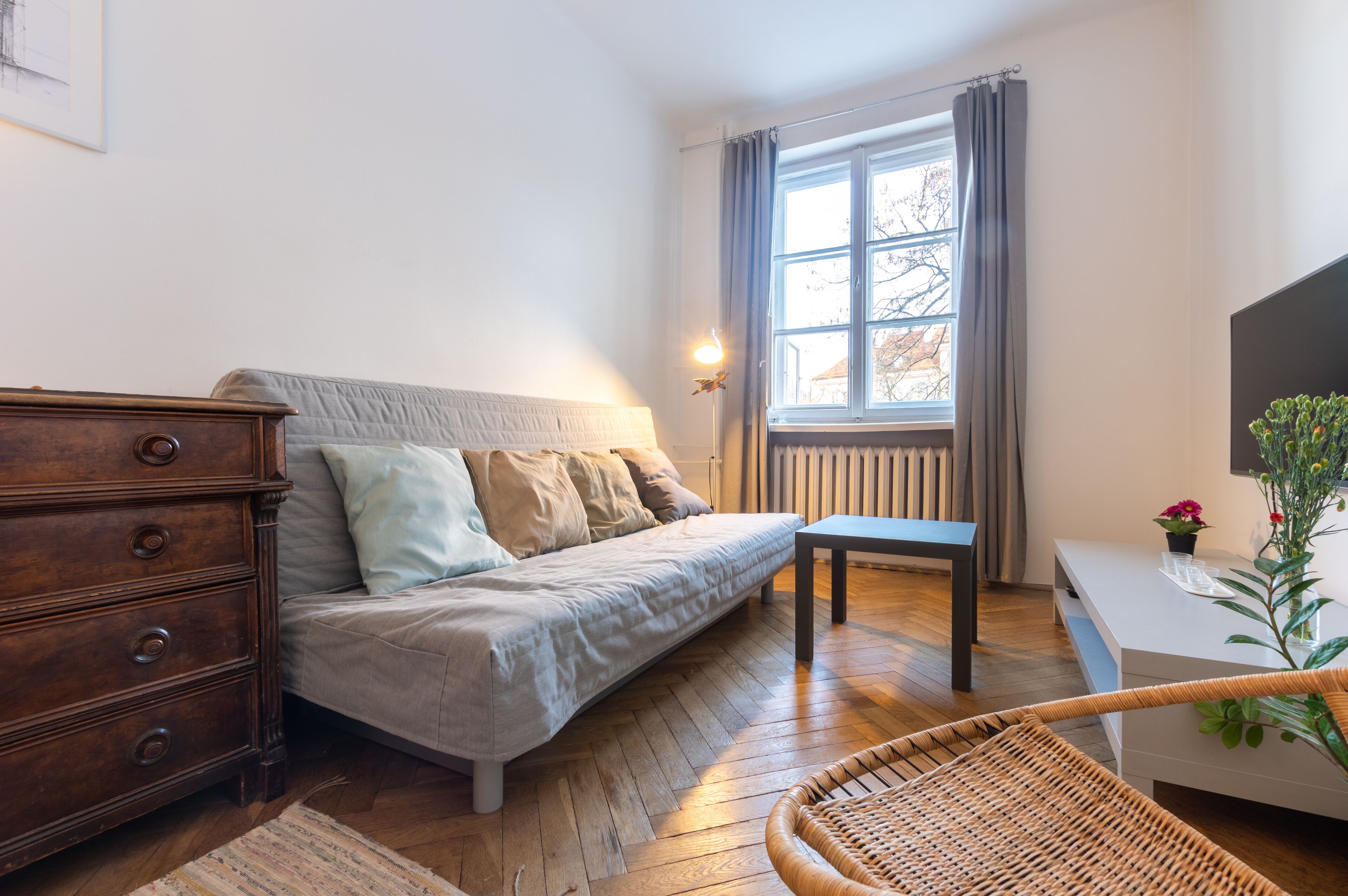 A cozy room with a sofa, wooden dresser, and a table.