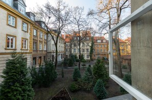 A courtyard with multiple buildings, trees, and a window frame. - Warsaw Concierge Old Town Square (Warsaw)