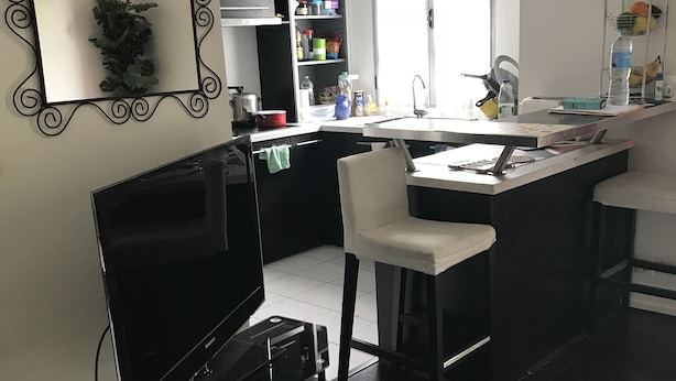 A modern kitchen with a built-in oven, a sink, and a dining area with a bar stool. - Disneyland paris esprit (Bussy-Saint-Georges)