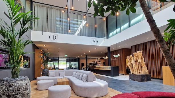 A modern lobby with a central seating area, a reception desk, and a large window overlooking the street. - Tailormade Hotel SIHLPARK Schindellegi (Feusisberg)