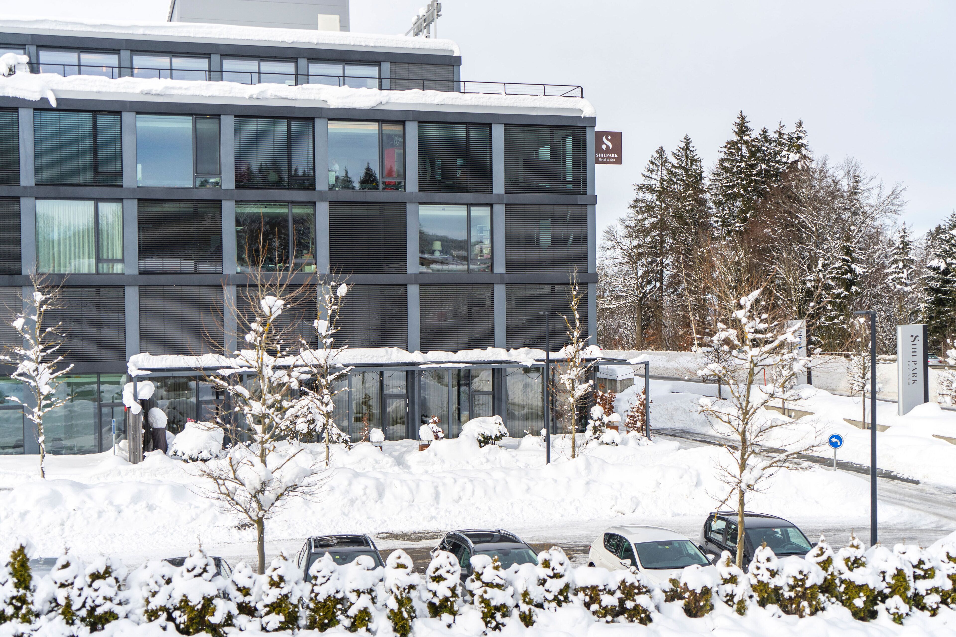 Un edifici modern amb nombroses finestres i un teulat cobert de neu.