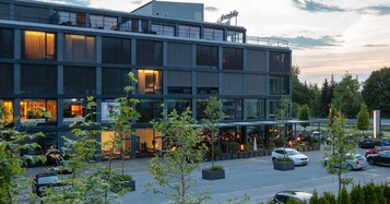 Un edificio moderno con varios niveles, ventanas amplias y zonas de estar al aire libre.