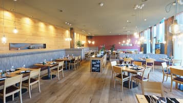 Un restaurante con mesas y sillas de madera, un menú en una pizarra y lámparas colgantes.