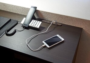 A desk with a telephone, a charging cable, and a smartphone. - After all station Chika is the most convenient   / Osaka Ōsaka (Osaka)