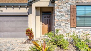 A residential building with a stone facade, a garage door, and a front door. - 3BR Home Near Legoland & Disney | Pool, Game Room, Balmoral Resort Amenities | Pet-Friendly (Haines City)