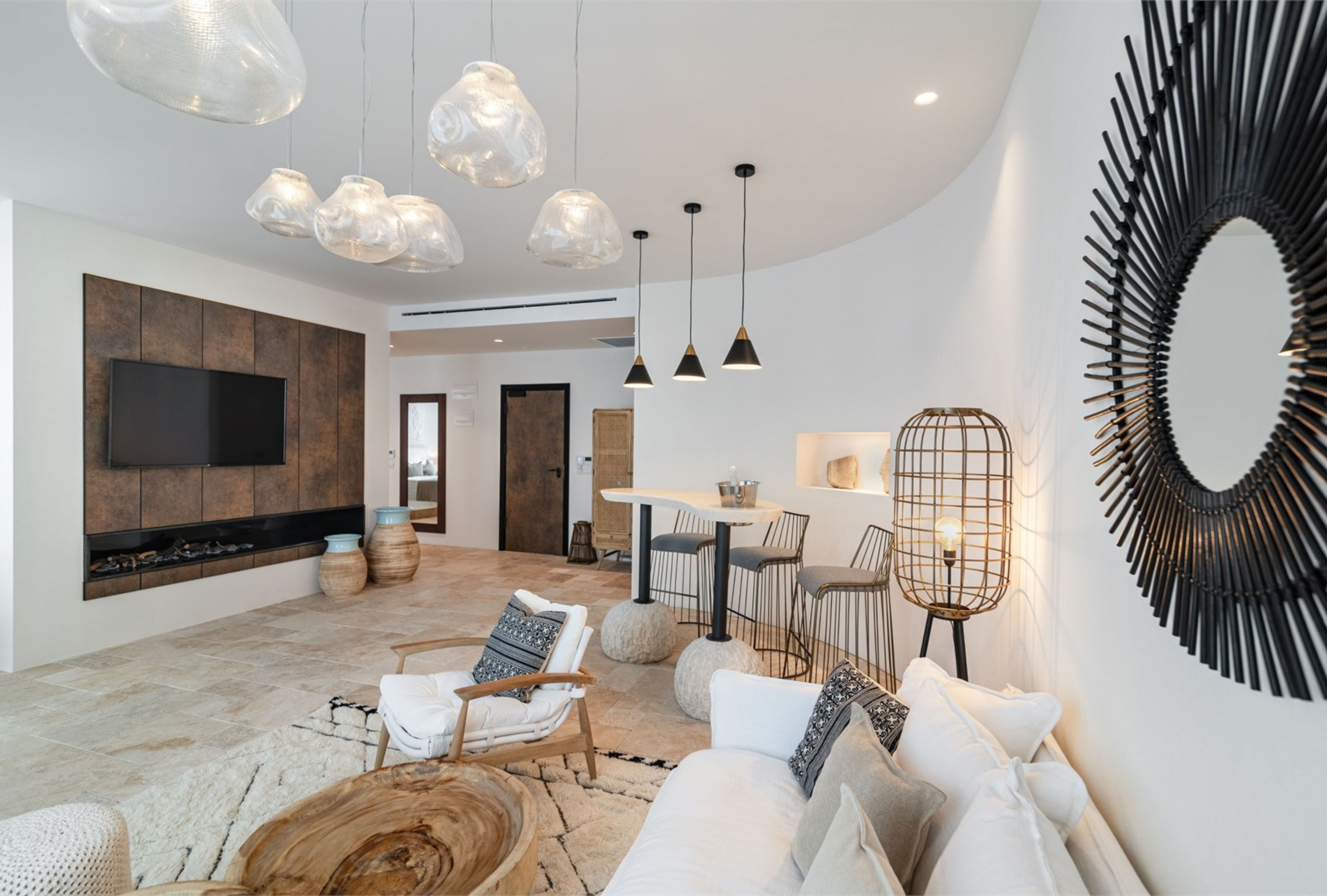 A modern living room with a flat-screen TV, wooden flooring, and a dining area with a round table and chairs.