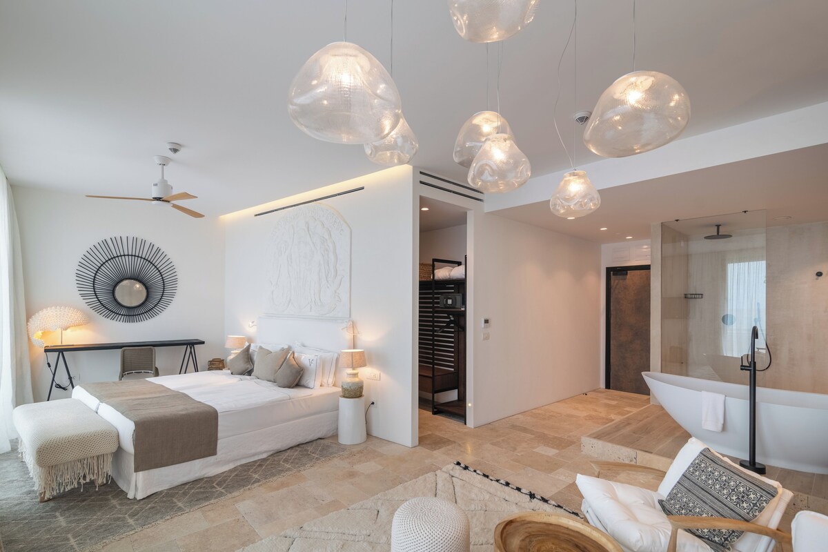 Une chambre moderne avec un lit, des tables de chevet, un bureau et un ventilateur de plafond.