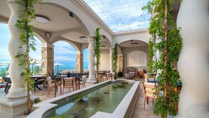 A covered outdoor area with a pool, seating, and views of the sea. - Villa Chinka by Astor Garden Hotel (Varna)