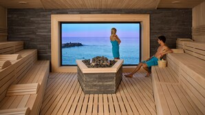 A sauna room with wooden benches, a stone fireplace, and a large window overlooking the sea. - Villa Chinka by Astor Garden Hotel (Varna)