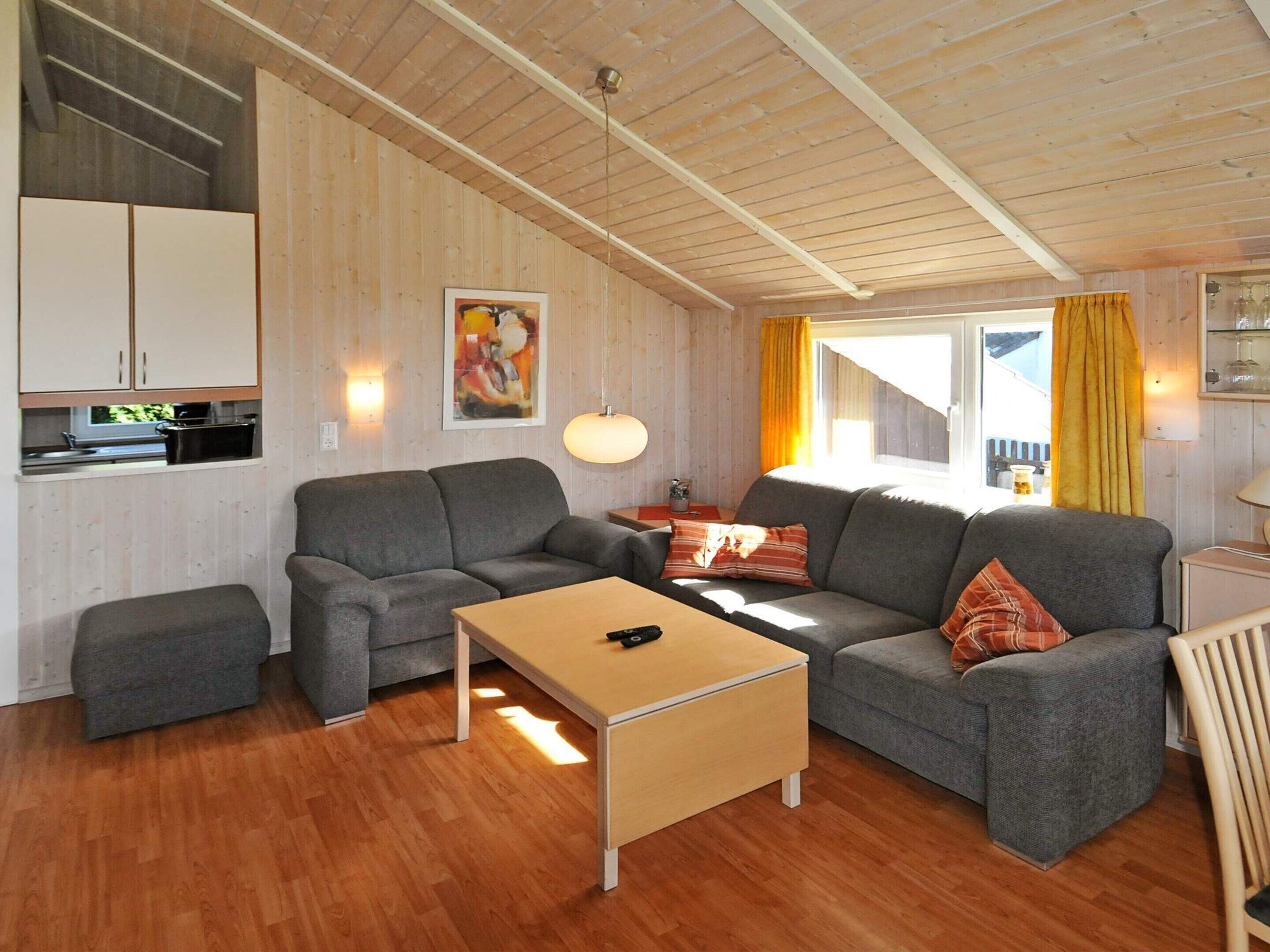 A modern living room with a sofa set, a coffee table, and a kitchen area with cabinets.