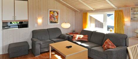 A modern living room with a sofa set, a coffee table, and a kitchen area with cabinets.