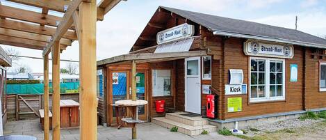 A wooden building with a sign reading 'Strand-Mast' and a 'Kiosk' sign.
