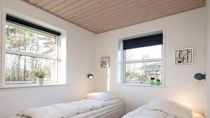 A bedroom with two single beds, a potted plant, a wall-mounted lamp, and a window with a view of trees. - Splendid Holiday Home in Laeso near Museum Court (Læsø)