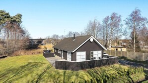 A modern house with a large garage, a fenced yard, and a well-maintained lawn. - Splendid Holiday Home in Laeso near Museum Court (Læsø)
