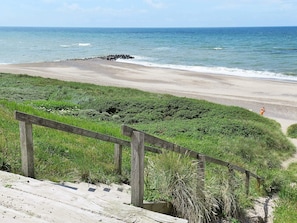 A coastal walkway with a wooden railing, leading to a sandy beach and the ocean. - 4 Star Holiday Home in Lemvig (Lemvig)