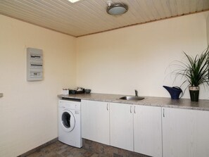 A compact kitchen with a built-in washing machine, a sink, and a potted plant. - 4 Star Holiday Home in Lemvig (Lemvig)