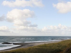 A coastal landscape with a beach, grassy dunes, and a rocky outcrop in the water. - 4 Star Holiday Home in Lemvig (Lemvig)