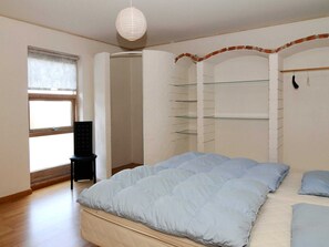 A bedroom with a bed, a chair, a wardrobe, and a hanging light fixture. - 4 Star Holiday Home in Lemvig (Lemvig)