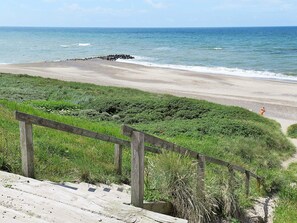 A beach with a wooden staircase leading down to the shore, surrounded by greenery. - 4 Star Holiday Home in Lemvig (Lemvig)
