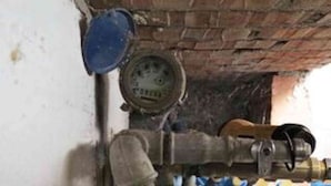 Een bakstenen muur met een meter en een pijp, mogelijk onderdeel van een gebouw.