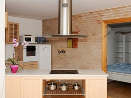 Una cocina compacta con horno empotrado, campana extractora de acero inoxidable y un refrigerador pequeño.