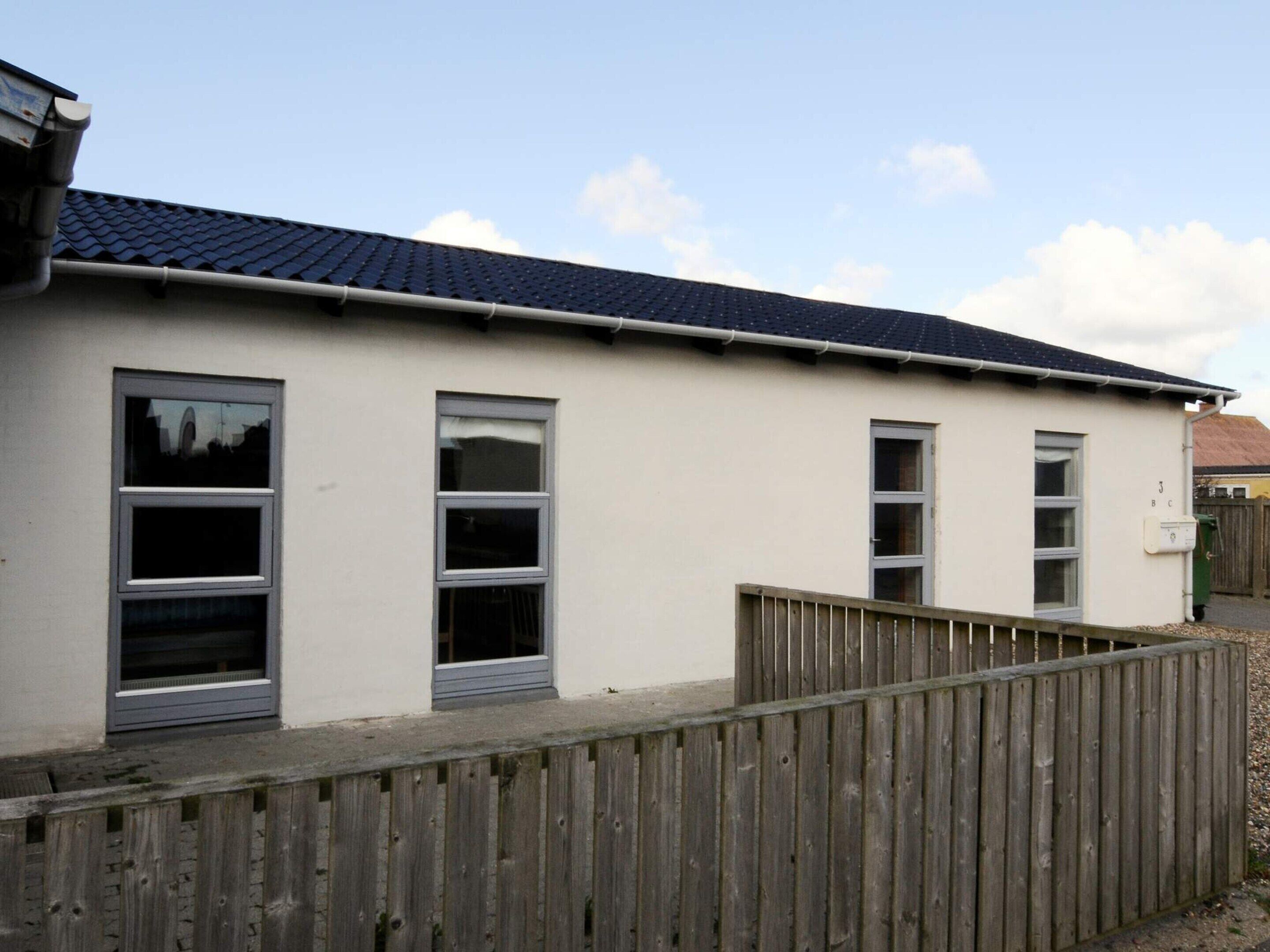 A single-story building with a flat roof and a wooden fence in front.