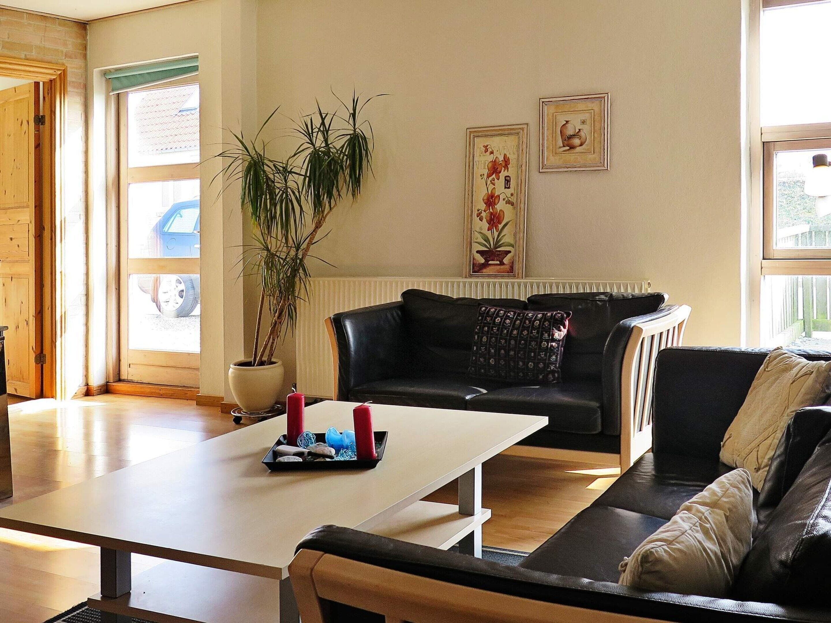 A living room with a sofa, a coffee table, a potted plant, and two framed pictures on the wall.