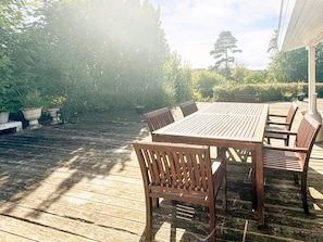 An outdoor wooden deck with a table and chairs, surrounded by greenery. - Splendid Holiday Home in Dronningmolle near Beach (Dronningmolle)