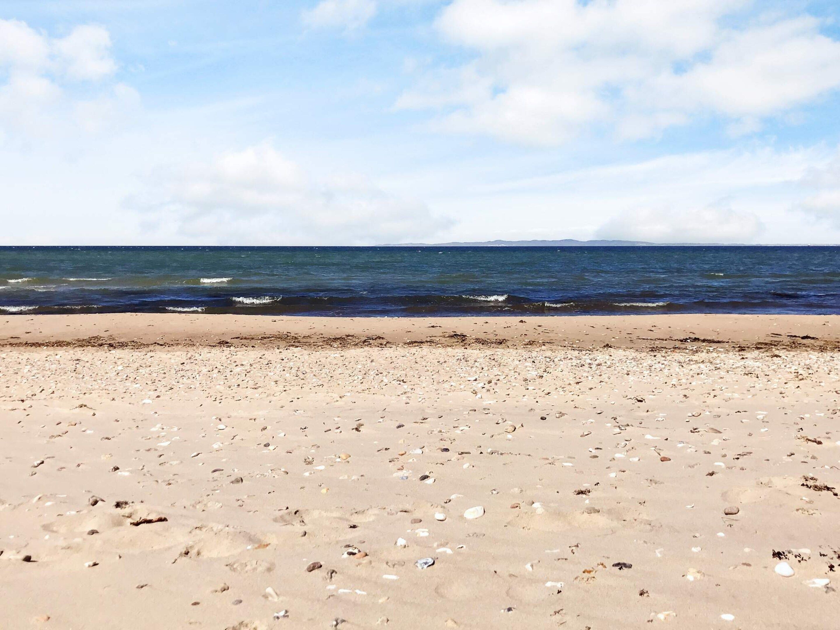 A beach with a sandy shore and scattered pebbles.