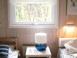 A room with a window, a bedside table with a lamp, and a bed with a striped pillow. - Splendid Holiday Home in Dronningmolle near Beach (Dronningmolle)