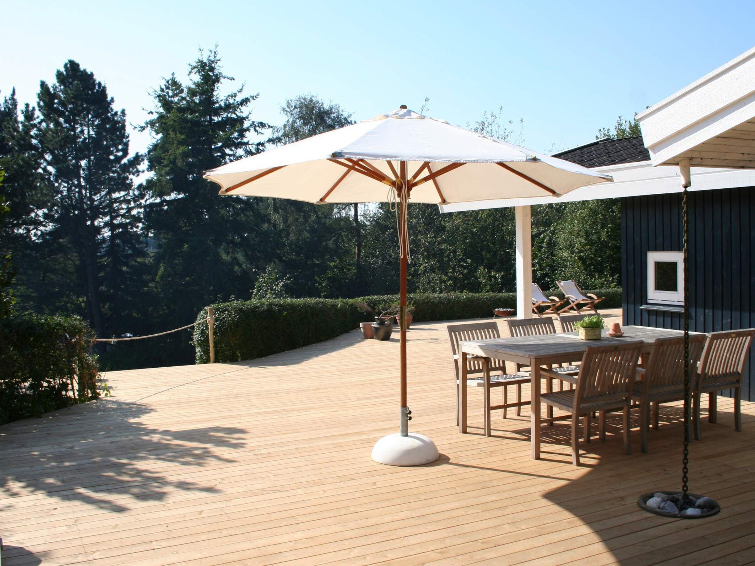 A wooden deck with a table and chairs, a hanging umbrella, and a TV mounted on the wall.