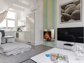 Una sala moderna con chimenea, un televisor de pantalla plana y un comedor con mesa y sillas.