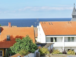 Un edificio costero con techo de tejas, una chimenea visible y una vista despejada del mar.