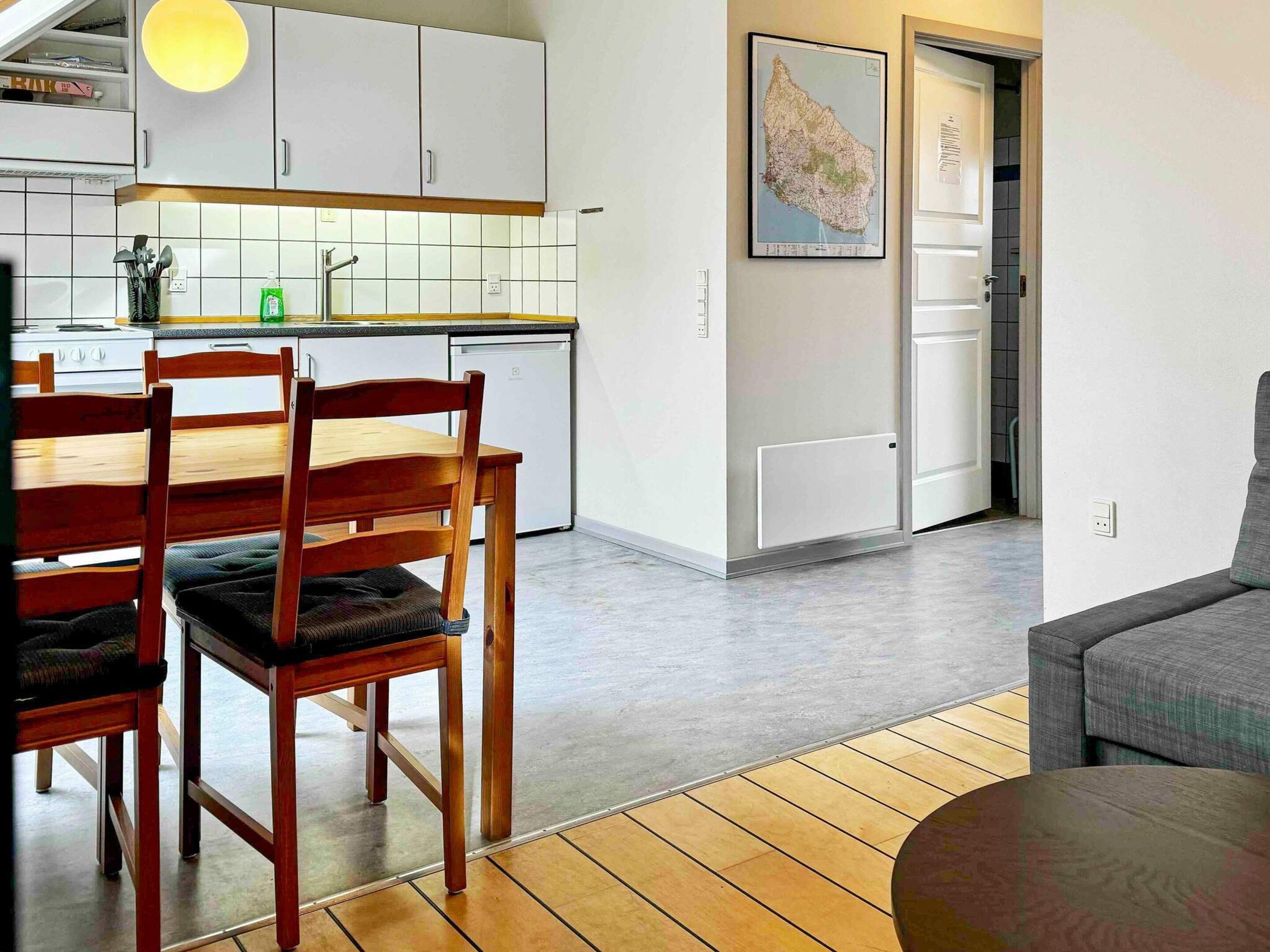 A modern kitchen with white cabinets, a dining table with chairs, and a map on the wall.