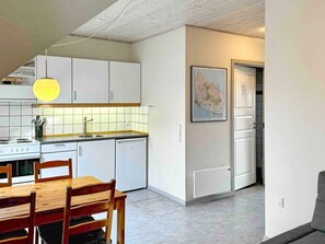 Una cocina moderna con armarios blancos, una mesa de comedor con sillas, una lámpara colgante y un mapa enmarcado en la pared.