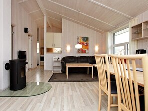 A modern interior with a wooden floor, a black sofa, a wooden dining table, and a glass coffee table. - Holiday Home in GrÃ¶mmitz (Groemitz)