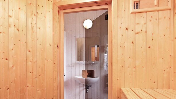 A wooden interior with a visible bathroom containing a sink and mirror. - Holiday Home in GrÃ¶mmitz (Groemitz)