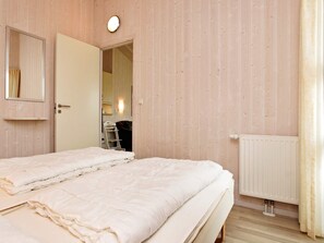 Une chambre avec deux lits, une porte donnant sur une salle de bain, un radiateur et un miroir au mur.