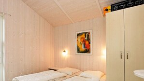 A room with two beds, wooden walls, a painting, and a cabinet. - Holiday Home in GrÃ¶mmitz (Groemitz)