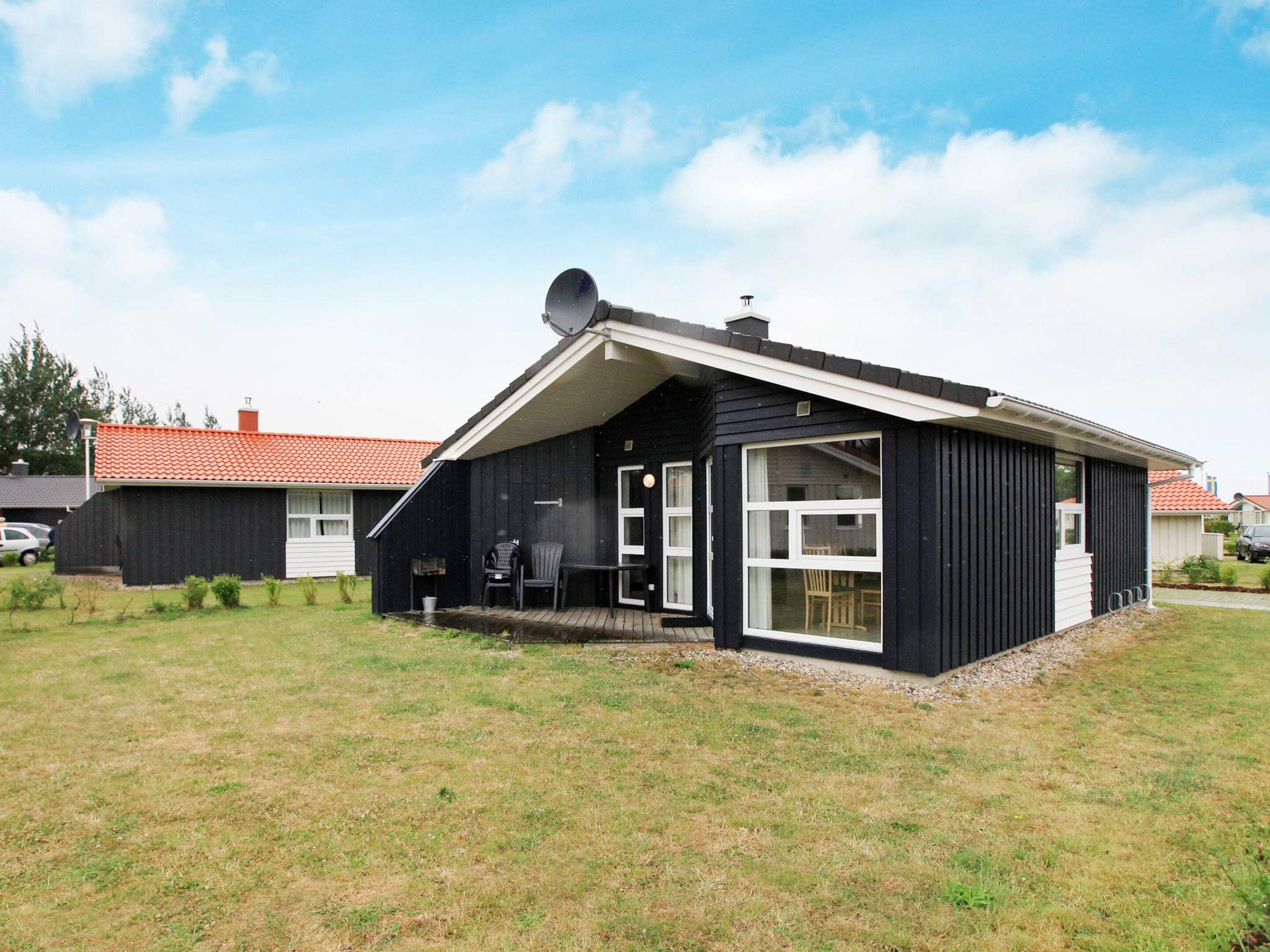 A modern black building with a sloped roof, a satellite dish, and a covered outdoor seating area.