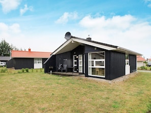 A modern black building with a sloped roof, a satellite dish, and a covered outdoor seating area.
