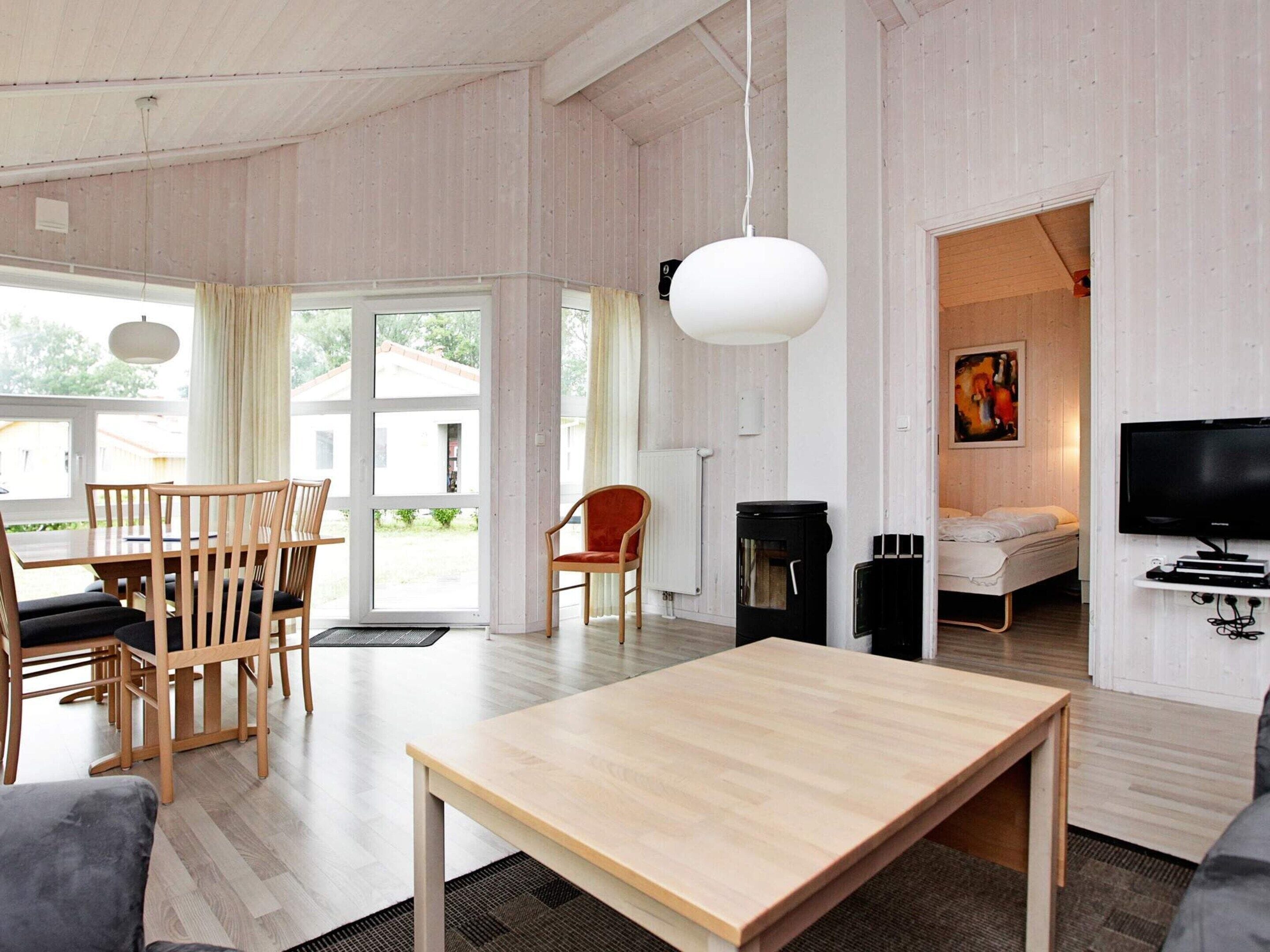 A modern living room with a dining area, a fireplace, a television, and a bedroom with a bed and a painting.