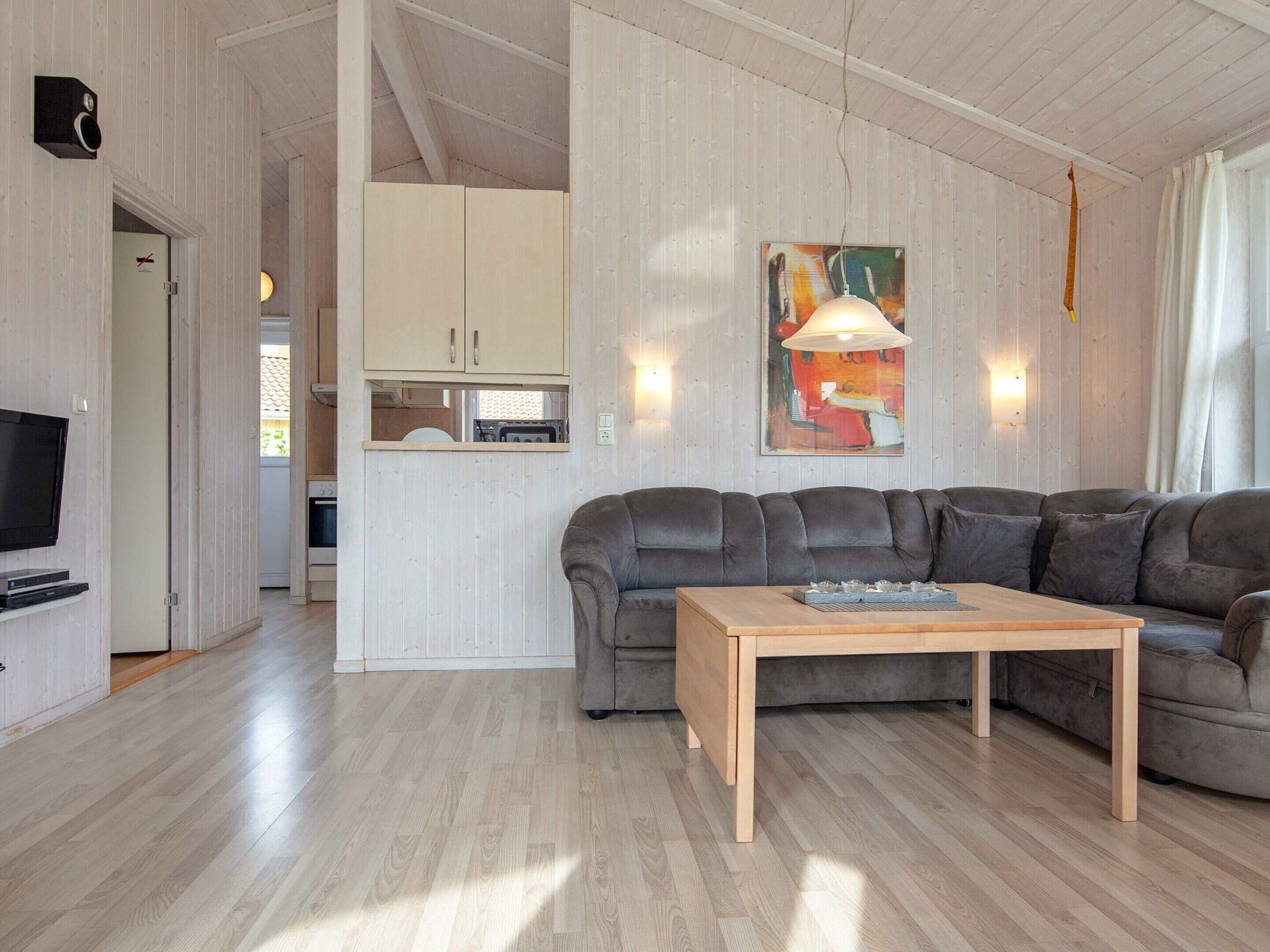A modern living room with a sectional sofa, a wooden coffee table, and a flat-screen TV.
