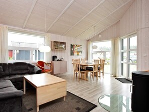 A spacious living area with a sofa, a dining table with chairs, a coffee table, and a glass-top table. - Holiday Home in GrÃ¶mmitz (Groemitz)